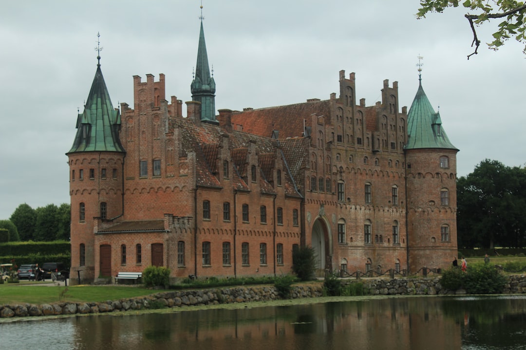 a large brick building with towers next to a body of water