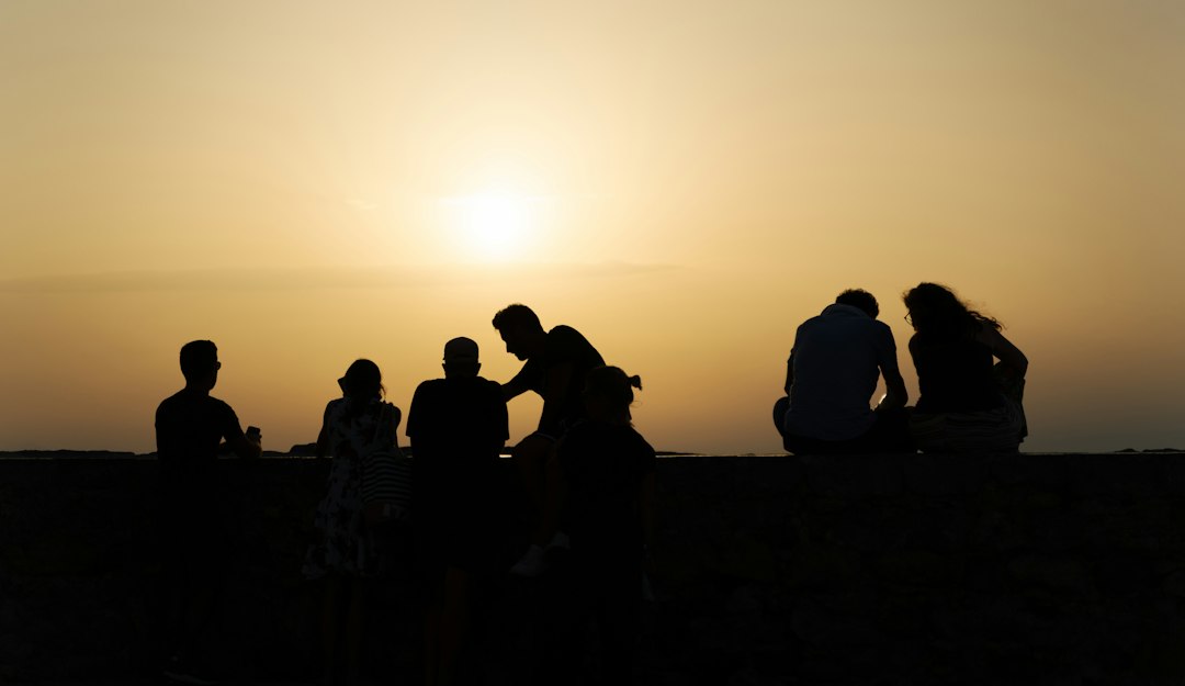 a group of people sitting on a bench looking at the sunset