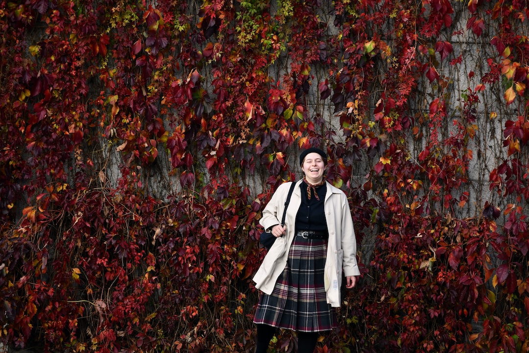 a woman standing in front of a wall covered in leaves