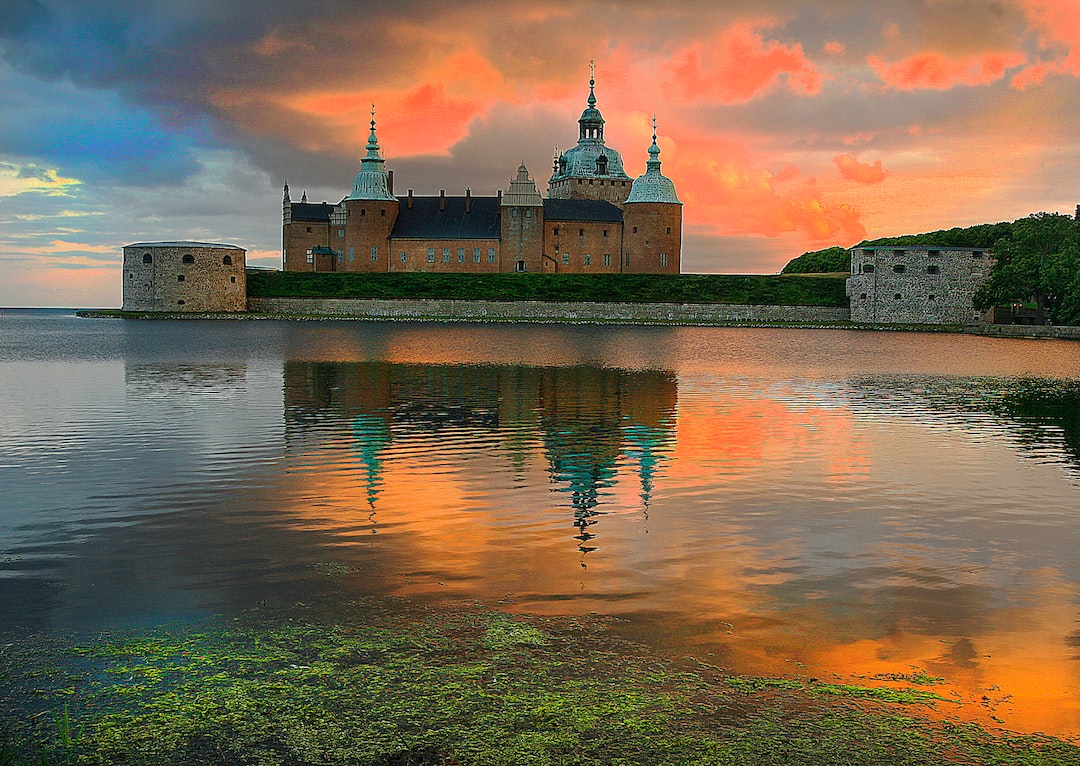 a large castle sitting on top of a lake under a cloudy sky